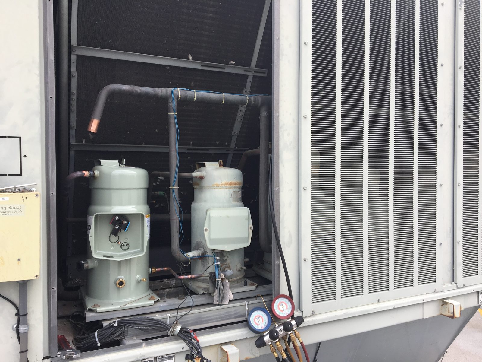 Compressor changeout inside a large Trane IntelliPak packaged rooftop unit, gauges connected